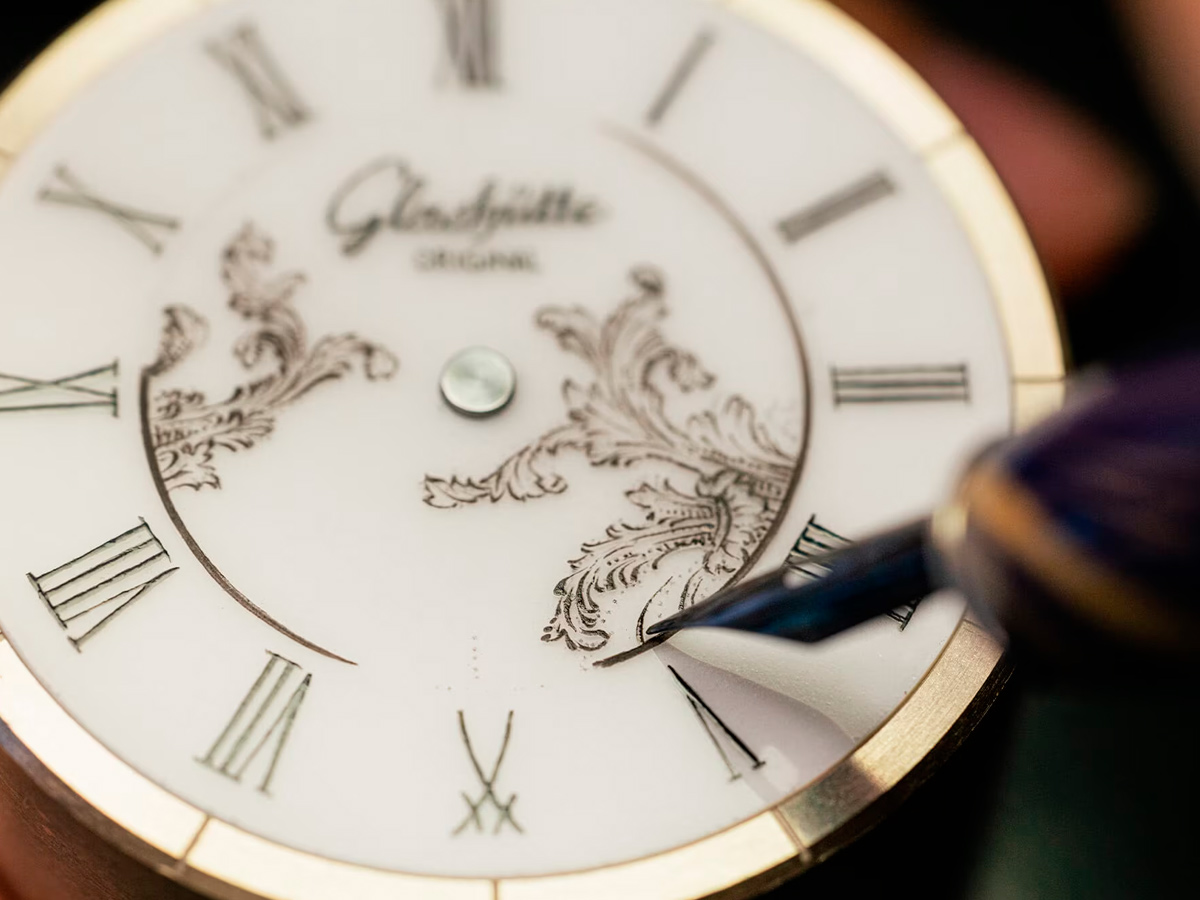 Artesano pintando a mano los detalles ornamentales de la esfera de porcelana Meissen del reloj Glashütte Original Senator Meissen.