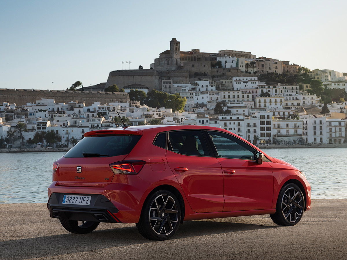 Vista trasera del SEAT Ibiza FR rojo con el casco antiguo de Ibiza de fondo