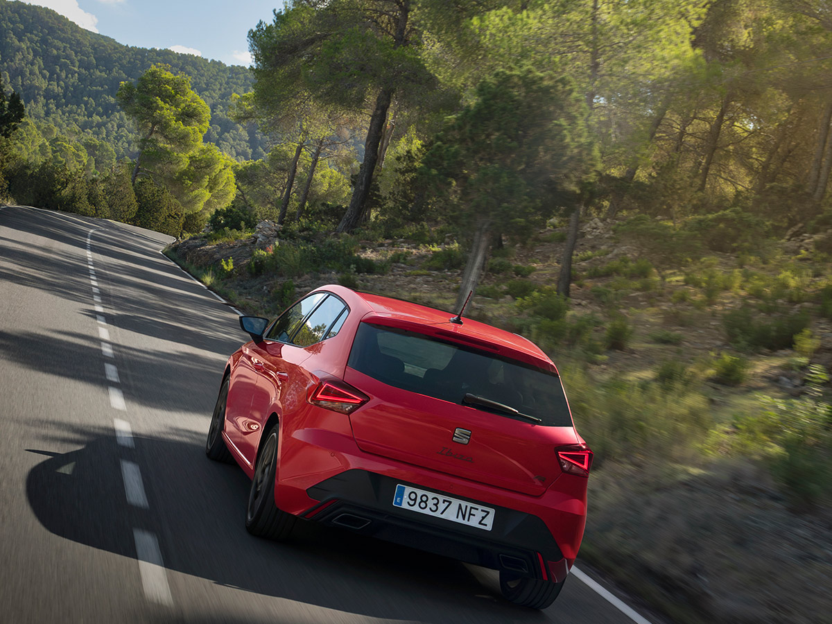 SEAT Ibiza FR rojo circulando por una carretera de curvas entre pinos