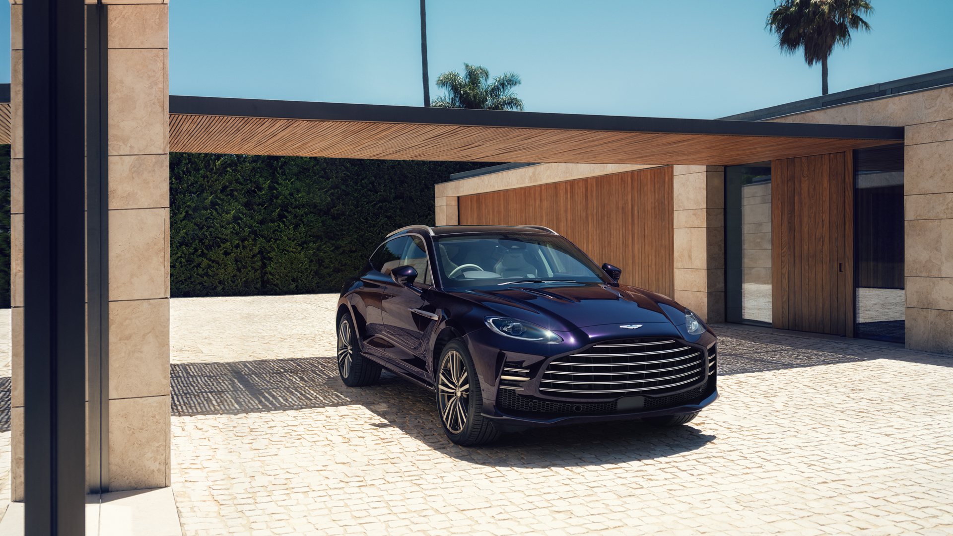 Aston Martin DBX GT 2026 visto de frente en tres cuartos, carrocería morada oscura y parrilla de doble lama