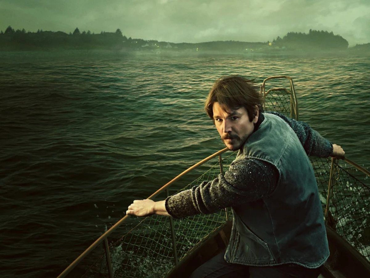 Josh Hartnett rema en una barca sobre un mar verdoso con la costa al fondo en Bajo la superficie