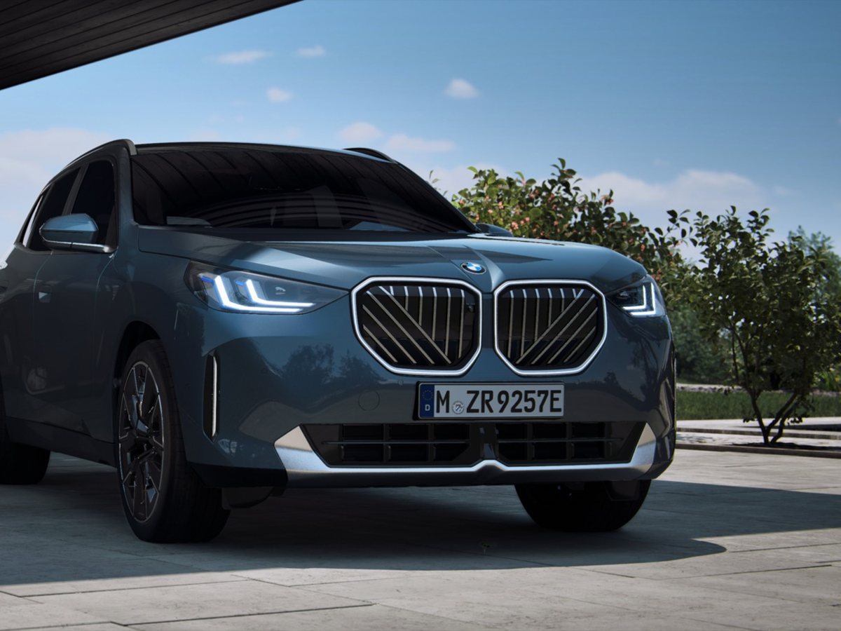 BMW X3 híbrido enchufable azul grisáceo de frente bajo el porche de una casa moderna