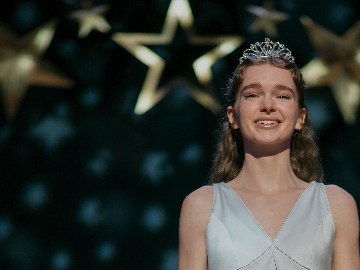Summer H. Howell, como Carrie White, sonríe con tiara y vestido claro en el baile de graduación de la serie Carrie