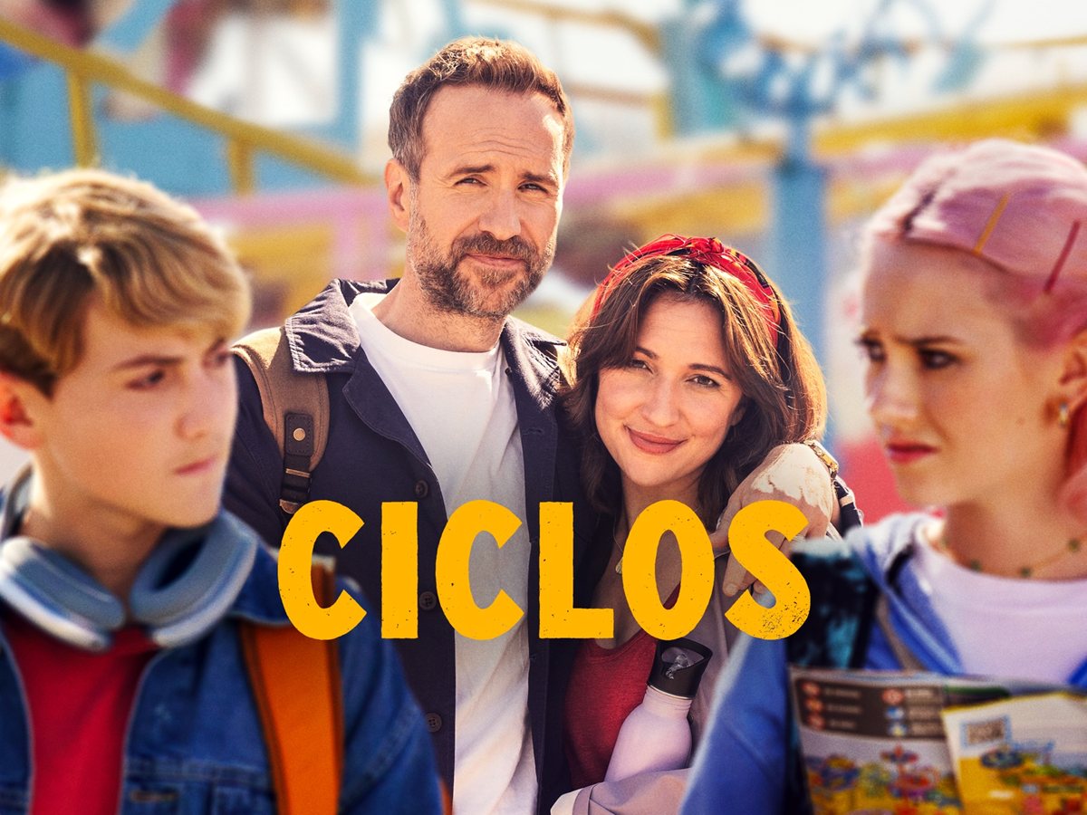 Rafe Spall y Esther Smith, como Jason y Nikki, junto a sus dos hijos adolescentes delante de un parque de atracciones en el arte de Ciclos