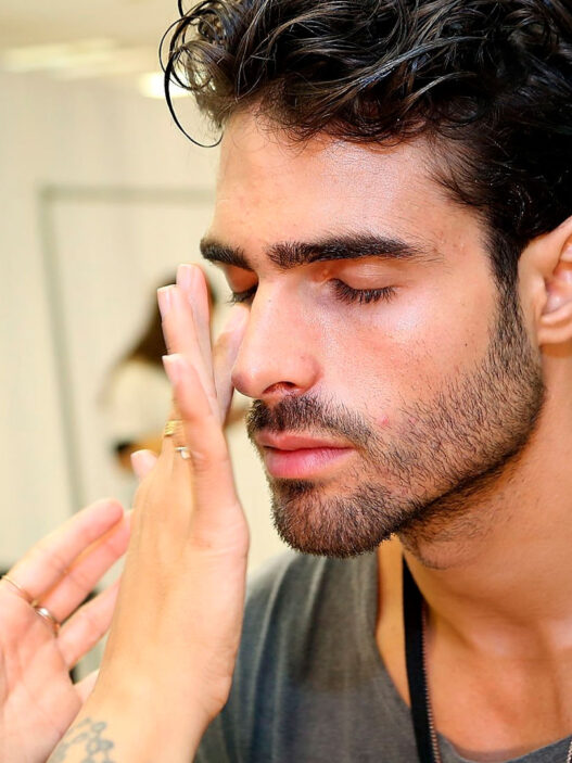 Modelo Juan Bettancourt poniéndose crema en la cara en backstage desfile