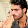Modelo Juan Bettancourt poniéndose crema en la cara en backstage desfile