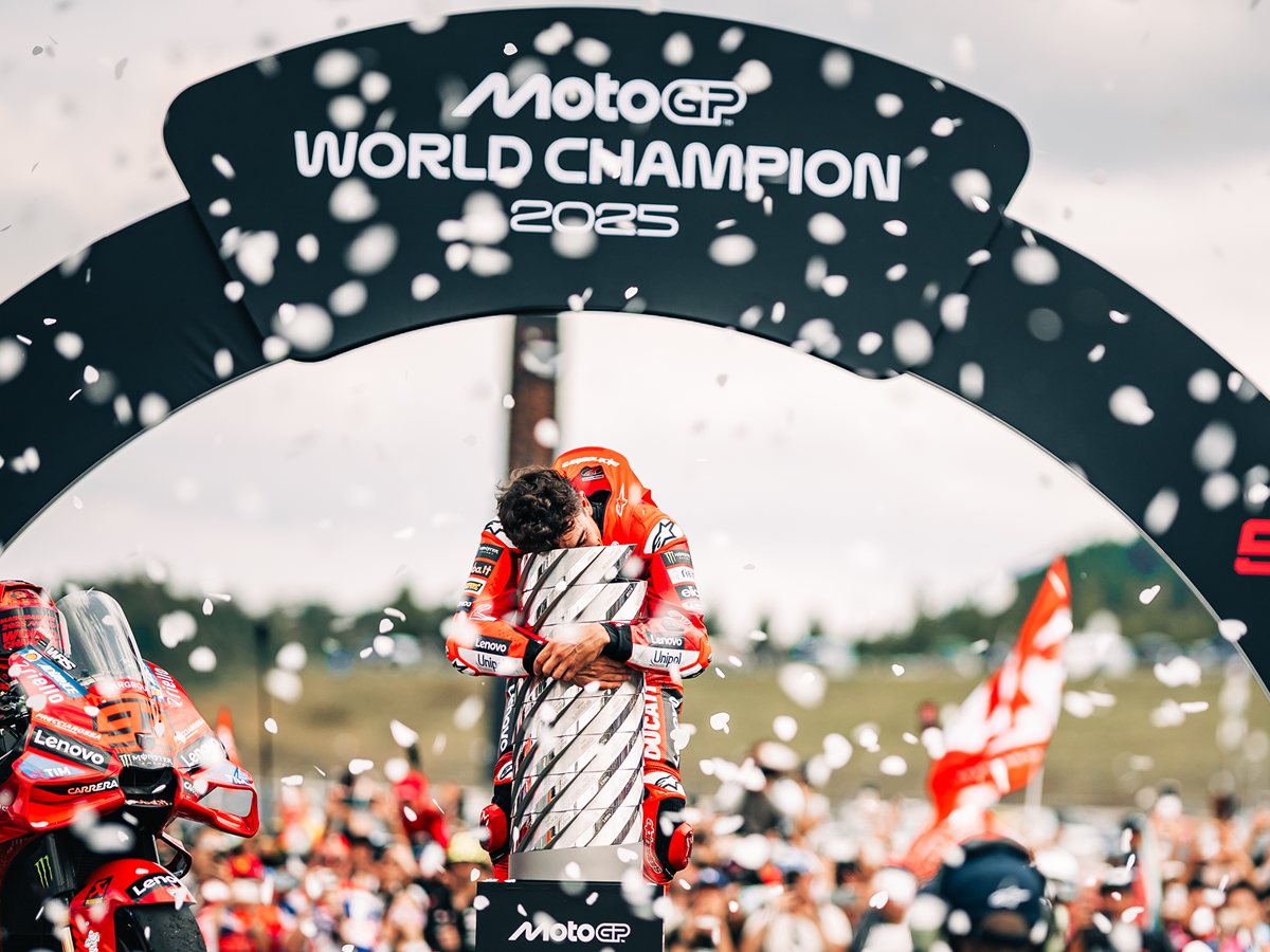 Marc Márquez celebra bajo el arco de campeón del mundo de MotoGP 2025 con confeti y su Ducati con el dorsal 93 al lado