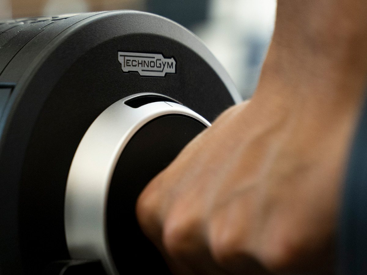 Primer plano de una mano agarrando una mancuerna Technogym en el gimnasio