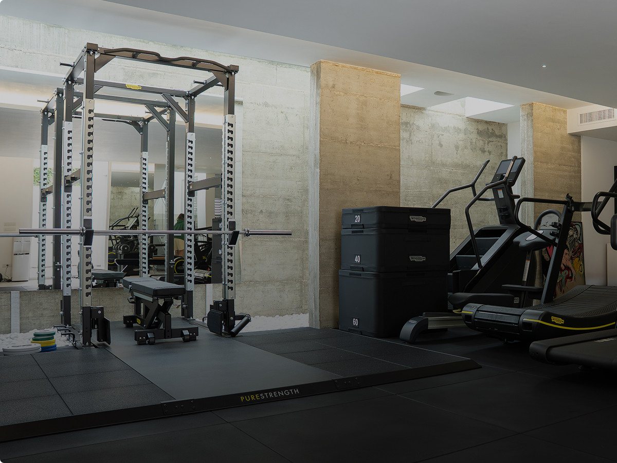 Rack de sentadilla con barra, banco plano y cajones pliométricos en una sala de entrenamiento de Technogym