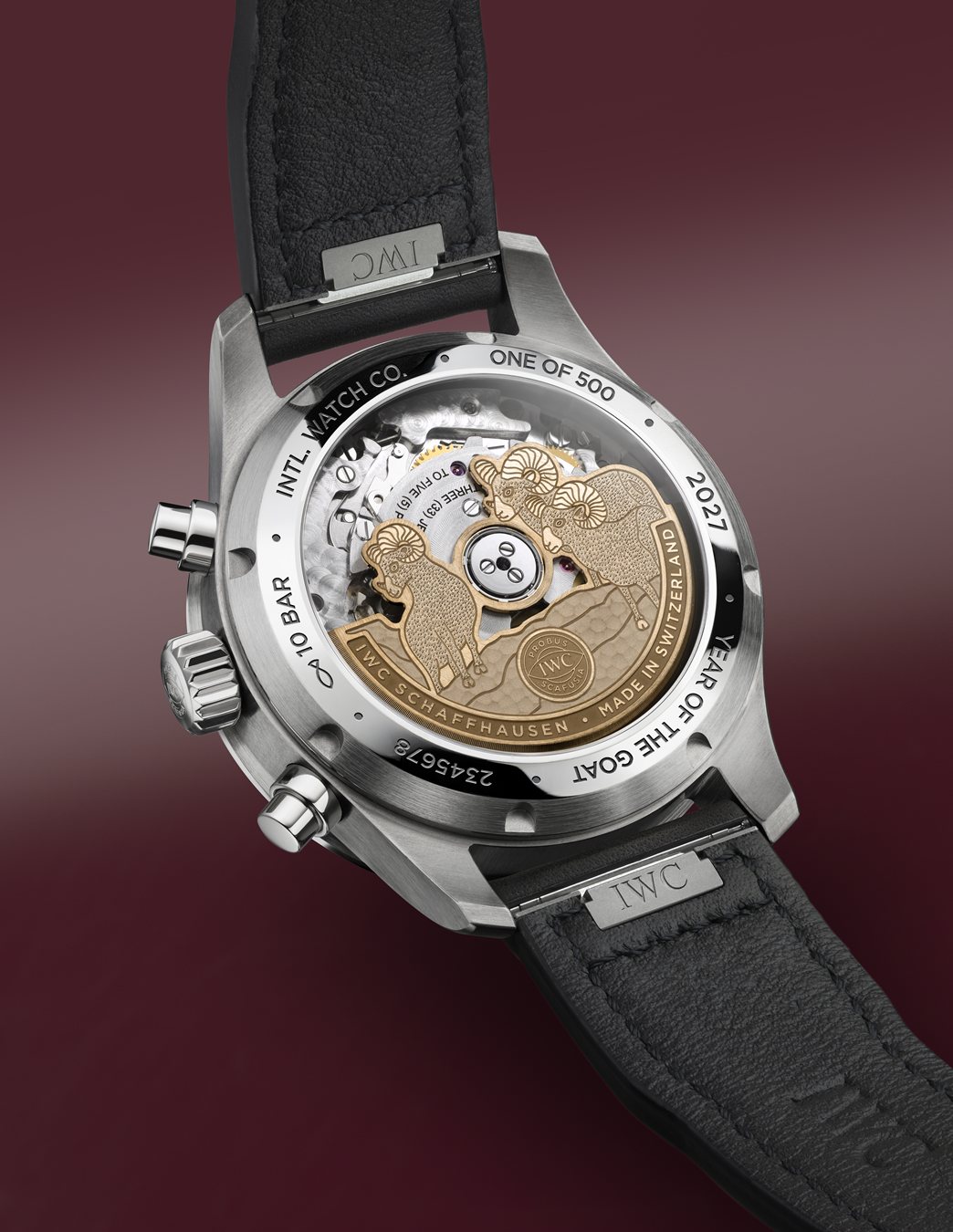 Reverso del IWC Pilot's Watch Performance Chronograph 41 Year of the Goat sobre fondo granate, con el rotor de 3 cabras y los pulsadores del cronógrafo