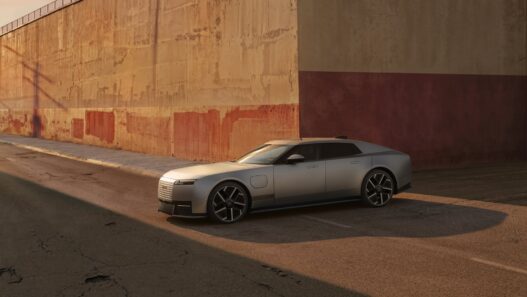Jaguar Type 01 en acabado plata satinado, de frente y de lado, aparcado junto a un muro ocre y rojo al atardecer