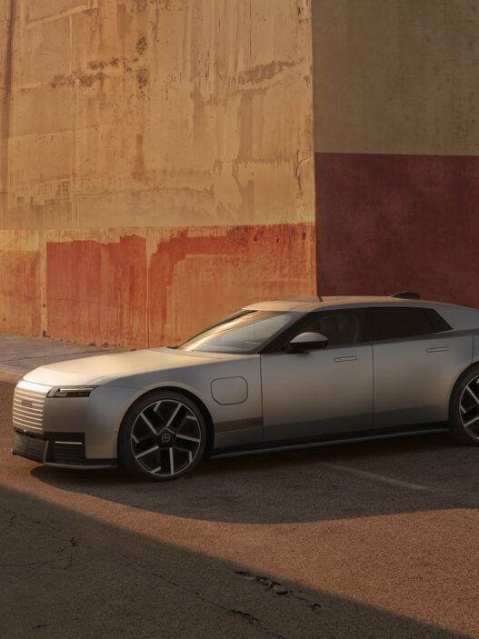 Jaguar Type 01 en acabado plata satinado, de frente y de lado, aparcado junto a un muro ocre y rojo al atardecer