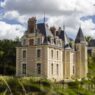 Château du Breuil de Les Sources de Cheverny, castillo de piedra clara con tejado de pizarra y torreón entre árboles del valle del Loira