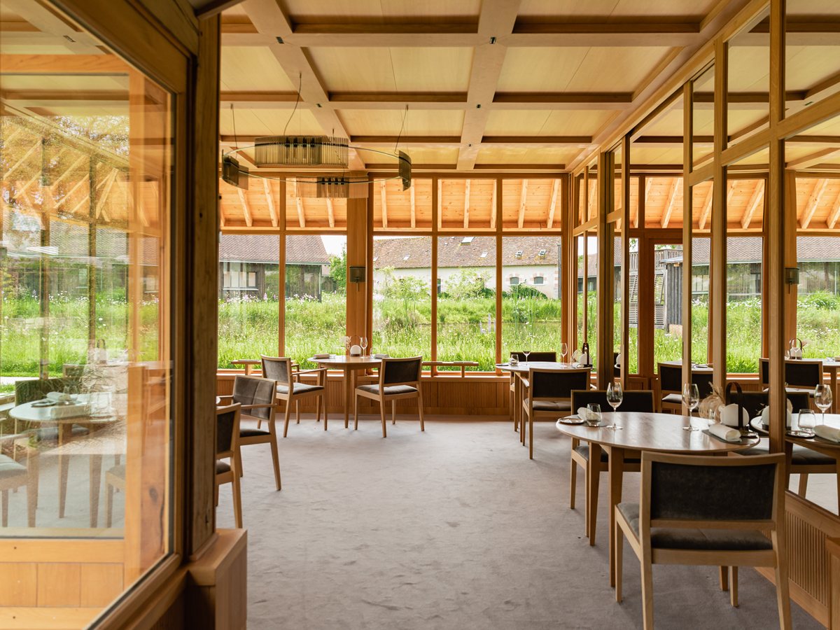 Comedor de Le Favori, restaurante con estrella Michelin de Les Sources de Cheverny, con techo de madera y cristaleras sobre los jardines y las casas del dominio