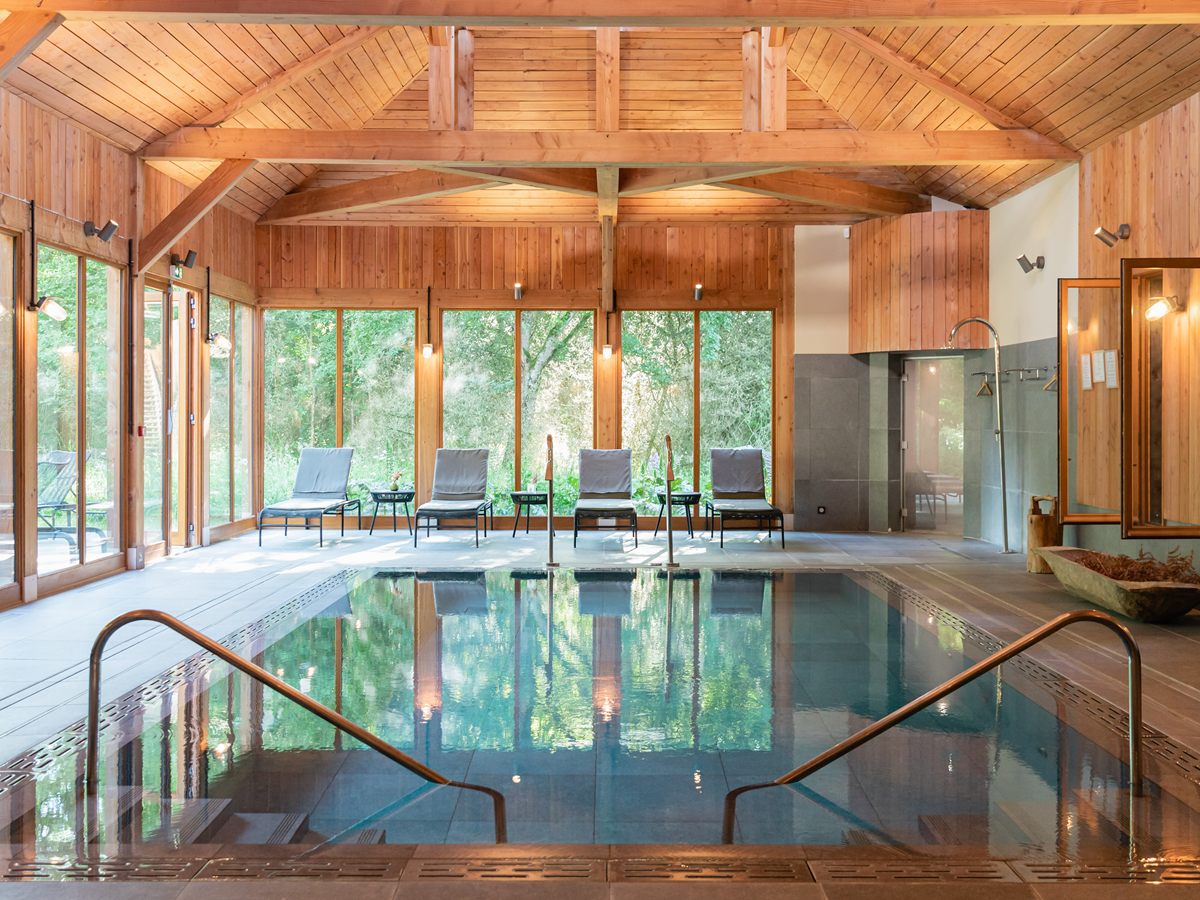 Piscina cubierta del Spa by Caudalie de Les Sources de Cheverny bajo un techo de madera con cristaleras al bosque