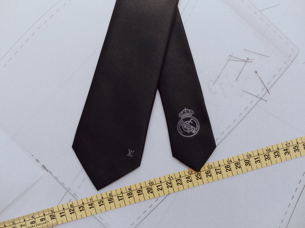 Corbata negra de Louis Vuitton con el escudo del Real Madrid bordado sobre un patrón de sastrería y una cinta métrica