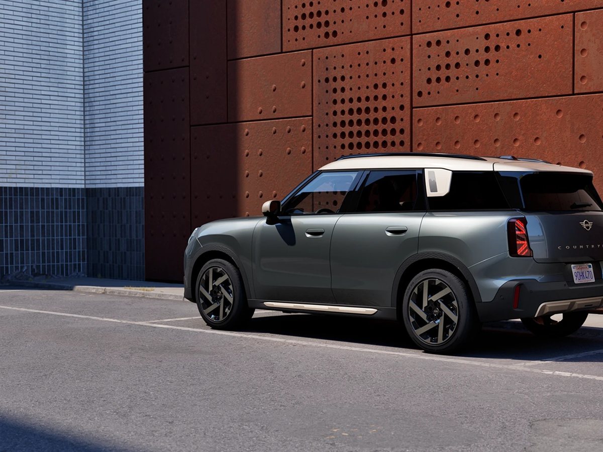 MINI Countryman verde de tres cuartos trasero aparcado junto a una fachada de acero oxidado