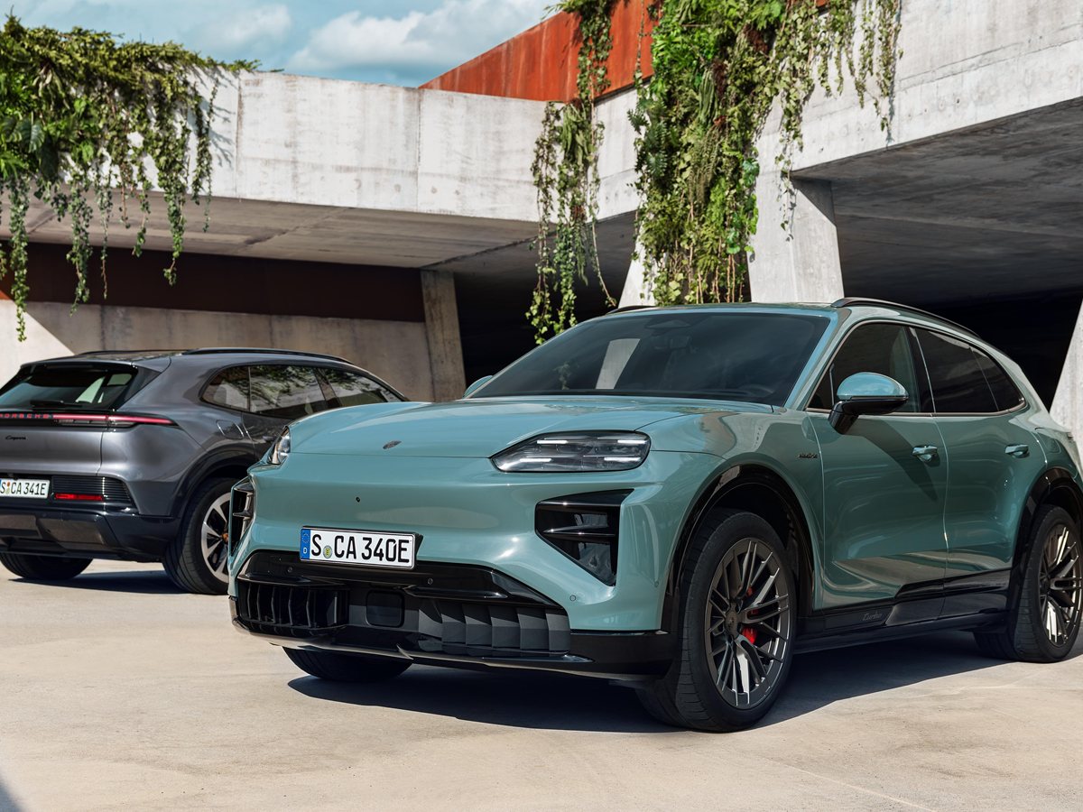 Porsche Cayenne Electric verde de tres cuartos delantero aparcado junto a un muro de hormigón