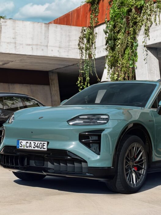 Porsche Cayenne Electric verde de tres cuartos delantero aparcado junto a un muro de hormigón