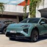 Porsche Cayenne Electric verde de tres cuartos delantero aparcado junto a un muro de hormigón