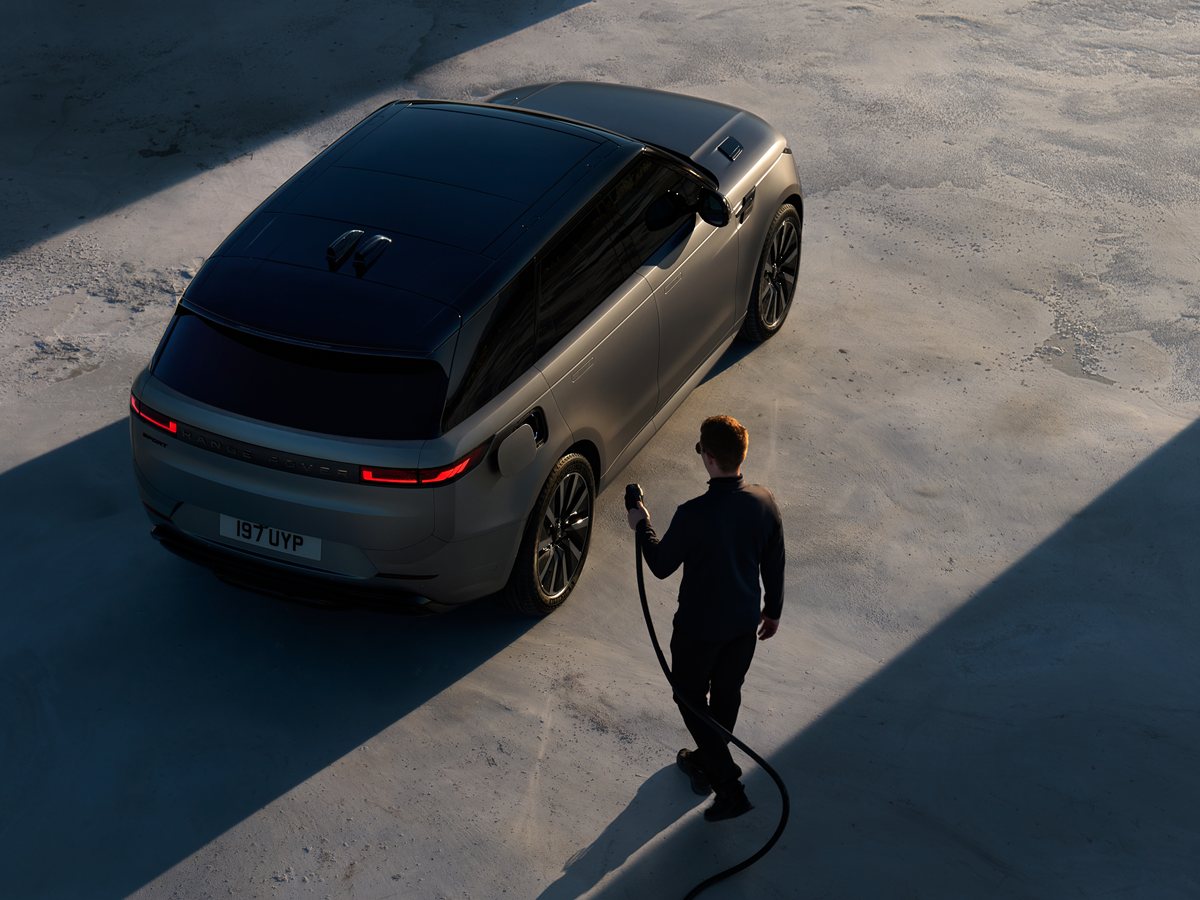 Range Rover Sport Electric visto desde arriba con una persona acercando el cable de carga a la toma trasera