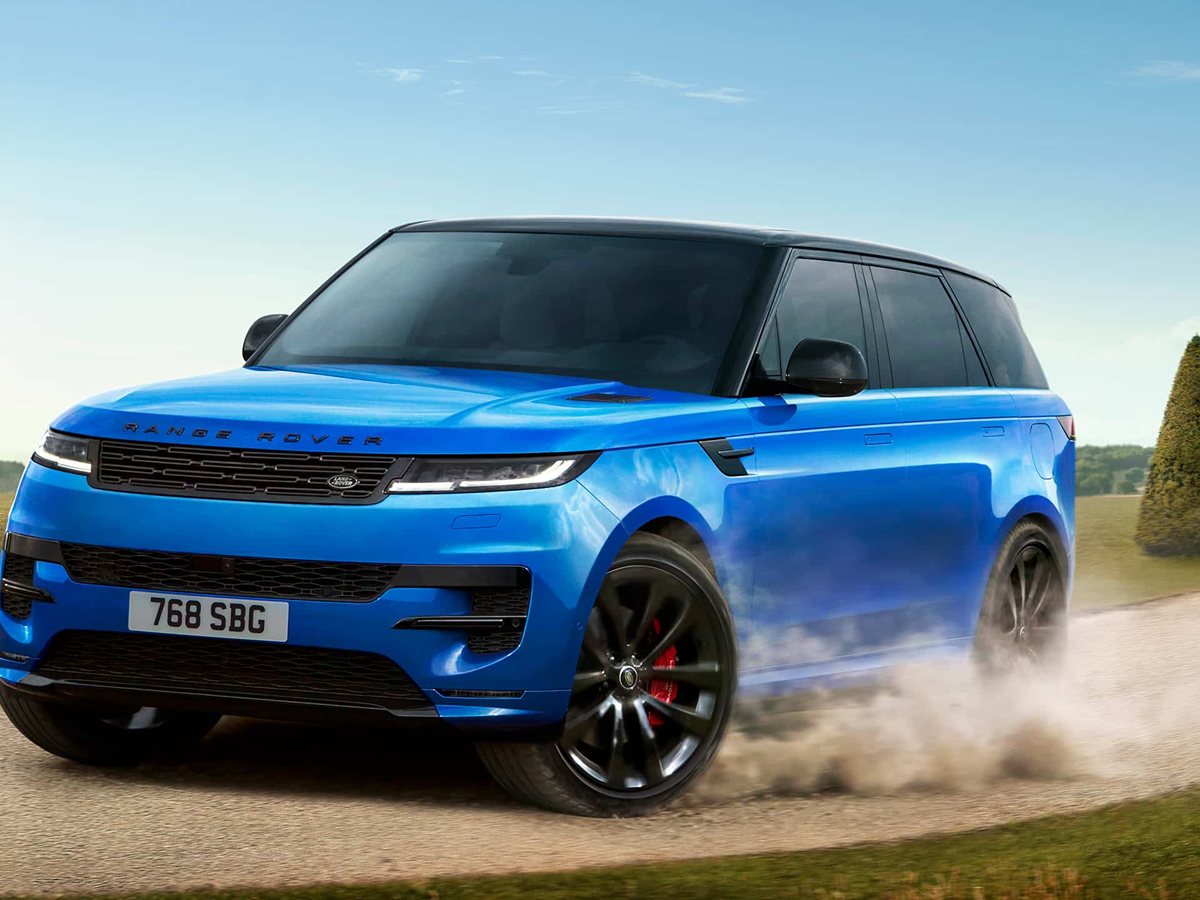 Range Rover Sport azul de tres cuartos delantero levantando polvo en un camino entre setos