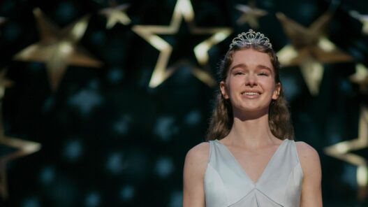 Summer H. Howell, como Carrie White, con tiara y vestido claro bajo estrellas doradas en el baile de la serie Carrie de Prime Video