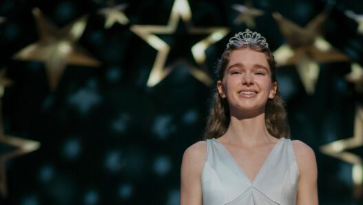 Summer H. Howell, como Carrie White, con tiara y vestido claro bajo estrellas doradas en el baile de la serie Carrie de Prime Video