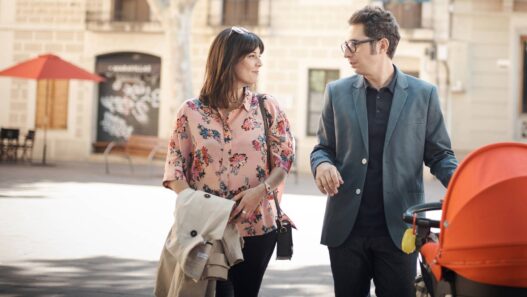 Eva Ugarte y Berto Romero, como Sandra y Berto, pasean con un carrito de bebé por la calle en Mira lo que has hecho, la serie de Movistar Plus+