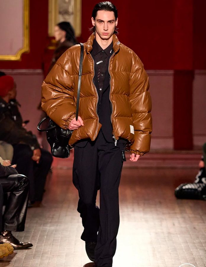 Modelo desfile Maison Mihara Yasuhiro vestido con Puffer y pantalón de vestir