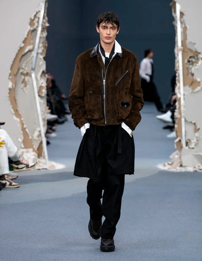 Modelo desfile SACAI otoño 2026 con chaqueta ante marrón