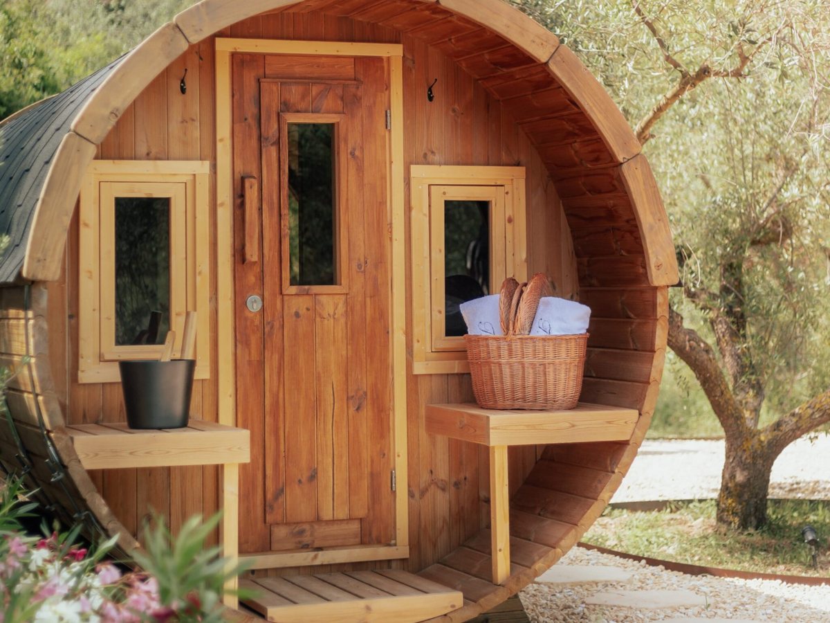 Sauna finlandesa de barril del spa Les Oliveres de Terra Dominicata junto a un olivo