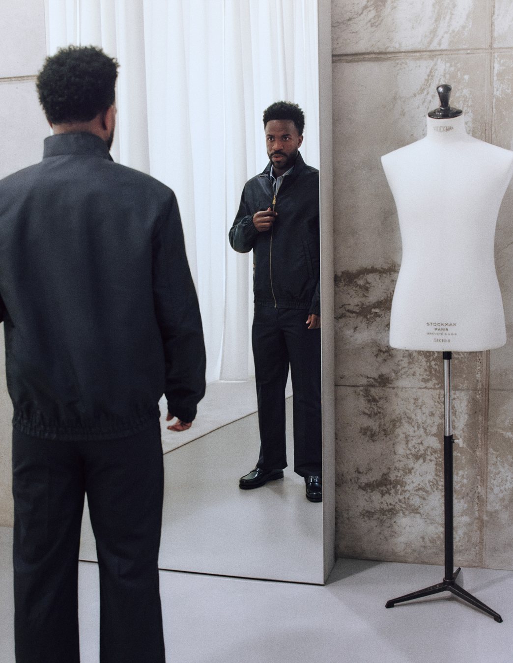Vinicius Jr. frente al espejo del probador con la chaqueta de nailon negra de Louis Vuitton
